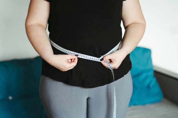 Woman measuring her waist and wondering how to stop hormonal weight gain